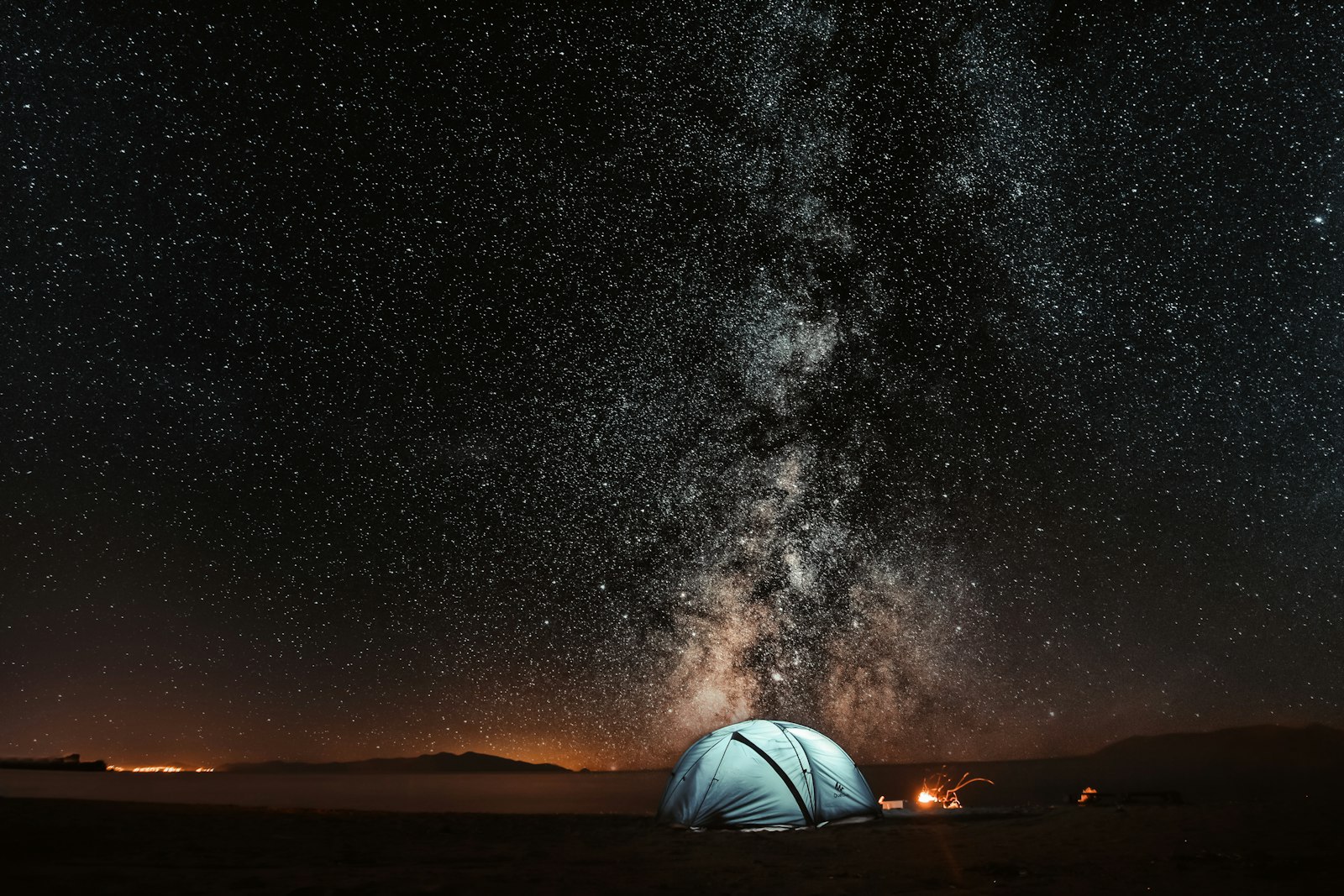 A tent glowing under a starry night sky